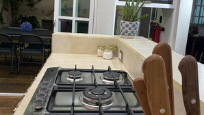 A kitchen with a gas stove, a sink, and a window overlooking a balcony.