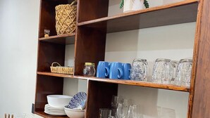 A kitchen with wooden shelves holding various kitchenware, a coffee maker, and a blender on the counter.