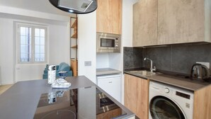 A modern kitchen with a built-in microwave, a washing machine, and a sink.