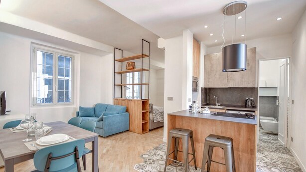 A modern apartment with a dining area, a living room with a sofa, a kitchen with a bar, and a bathroom.