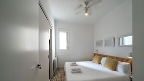 Een hotelkamer met een bed, plafondventilator, raam en radiator.