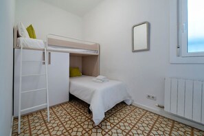 A small, clean room with a bunk bed, a wardrobe, a radiator, and a window.