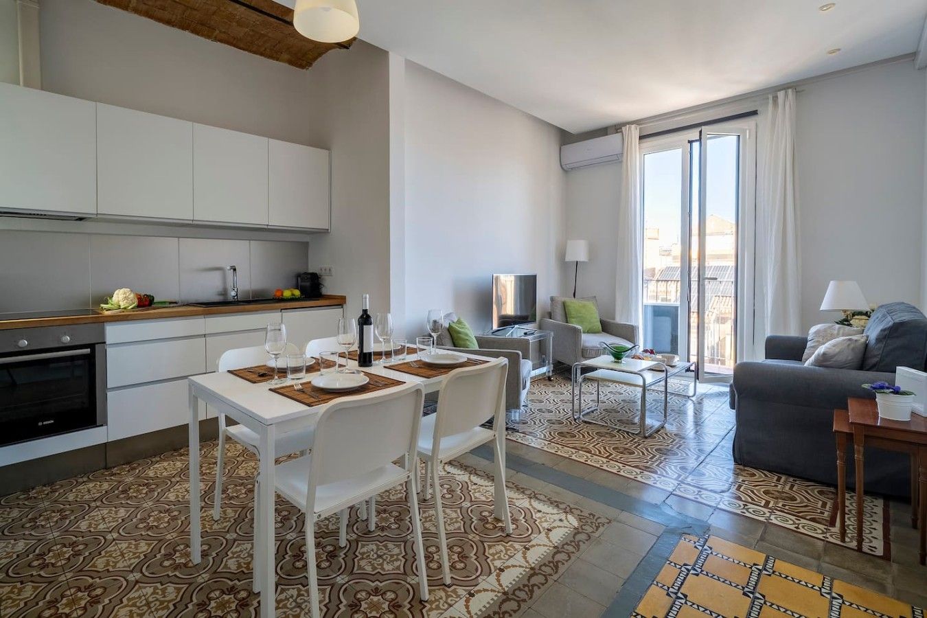 A modern apartment with a dining area, kitchen, living room, and a balcony with a view.