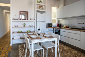 A compact kitchen with white cabinetry, a dining table set for two, and a microwave above the counter.
