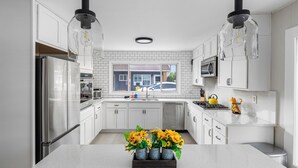 A modern kitchen with white cabinets, stainless steel appliances, and a central island with a flower arrangement. - Pleasant Valley Resort (Arcadia)