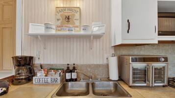 A kitchen with a coffee bar, a Farm House sign, a coffee maker, and a toaster oven.