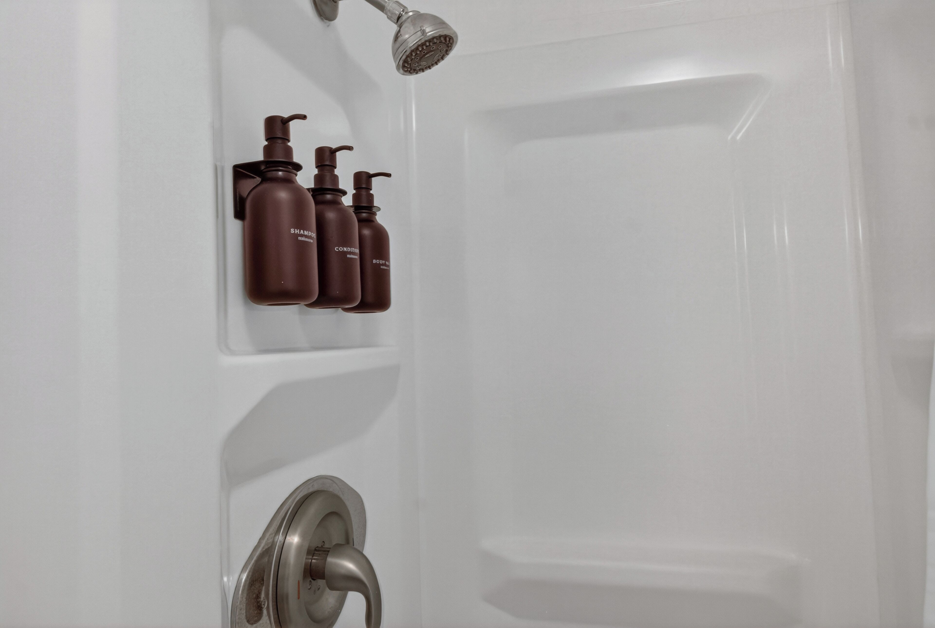 A bathroom with a shower, a wall-mounted soap dispenser, and a faucet.