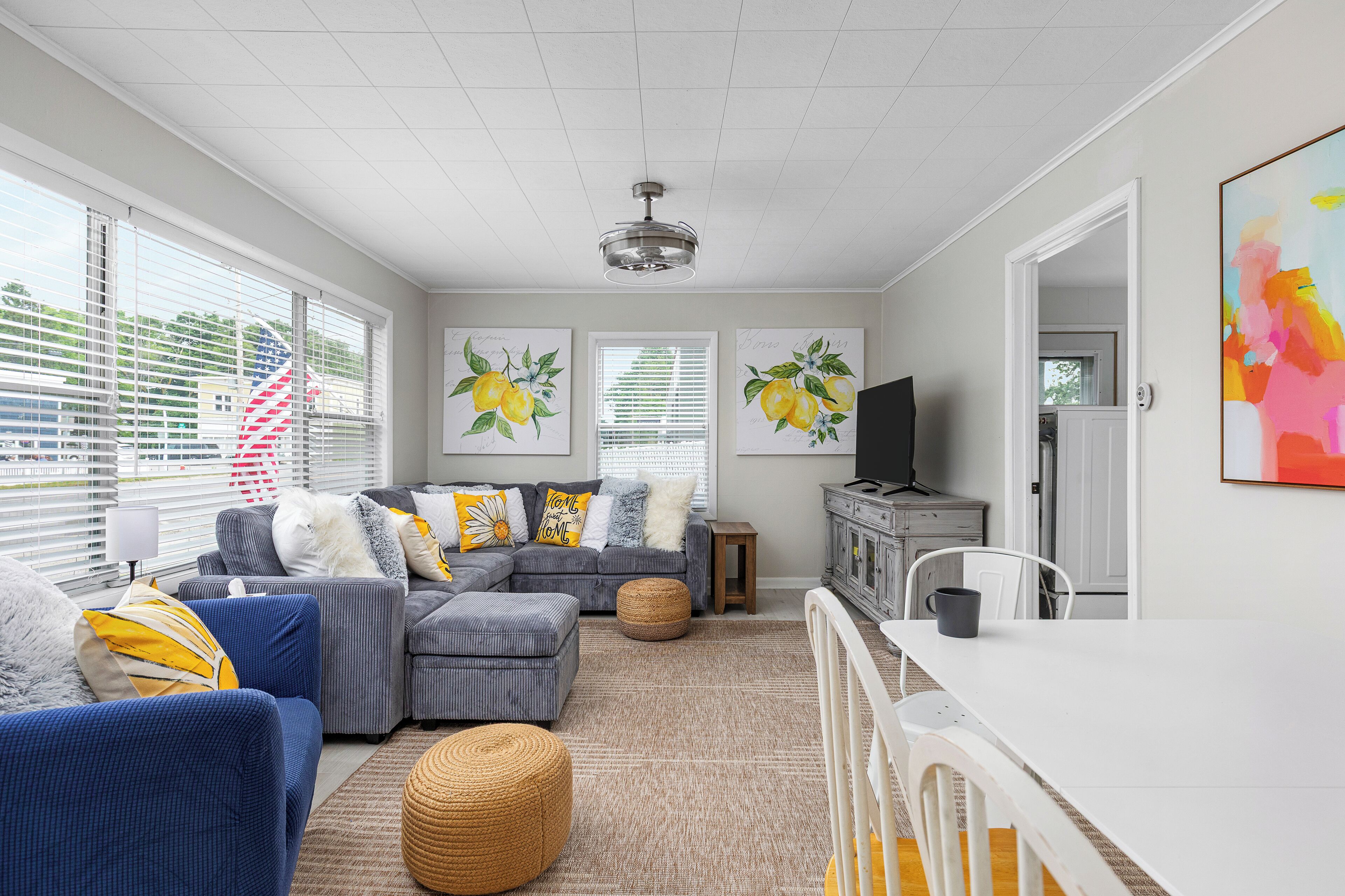 A modern living room with a sectional sofa, ottoman, and a dining table.