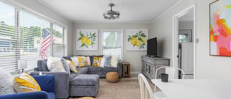 A modern living room with a sectional sofa, ottoman, and a dining table.