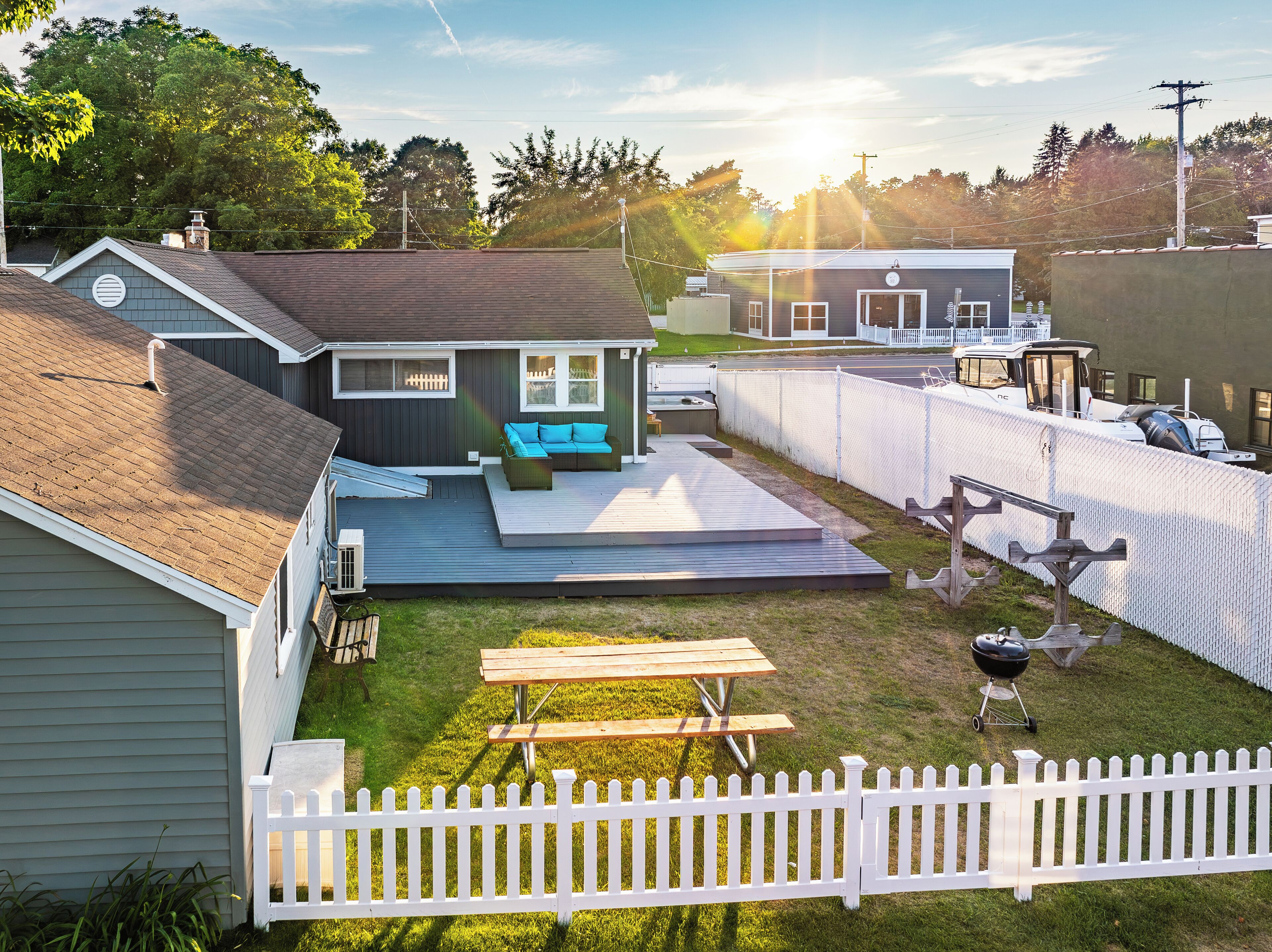 A backyard with a wooden deck, a barbecue grill, and a white picket fence.