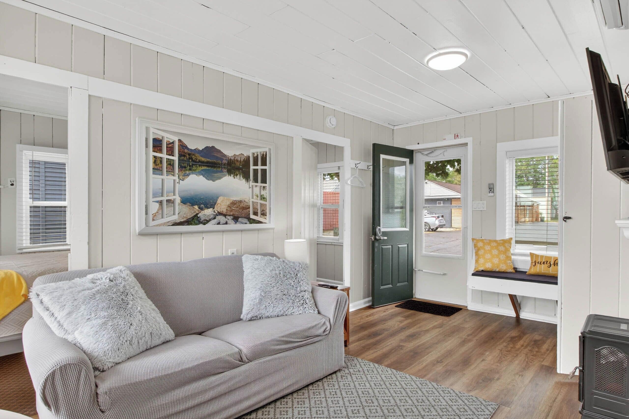 A cozy room with a sofa, a bench, a painting, and a door.