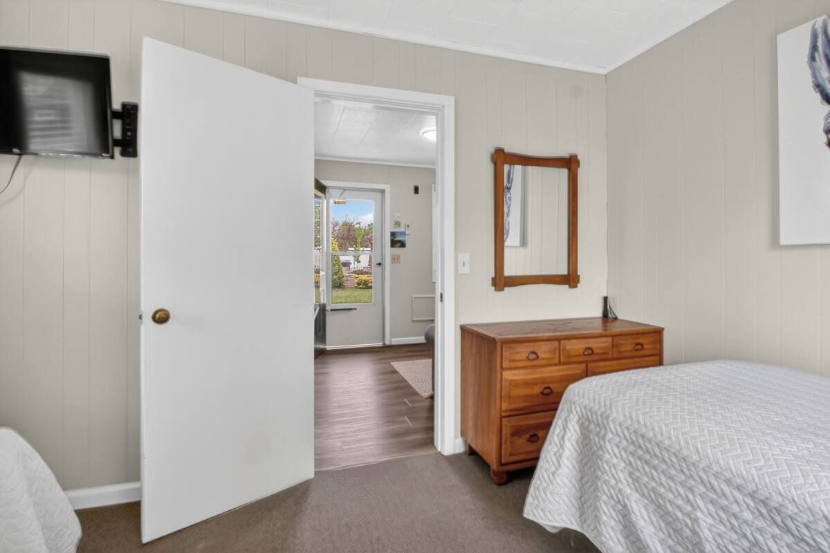 A bedroom with a bed, dresser, and a television mounted on the wall.