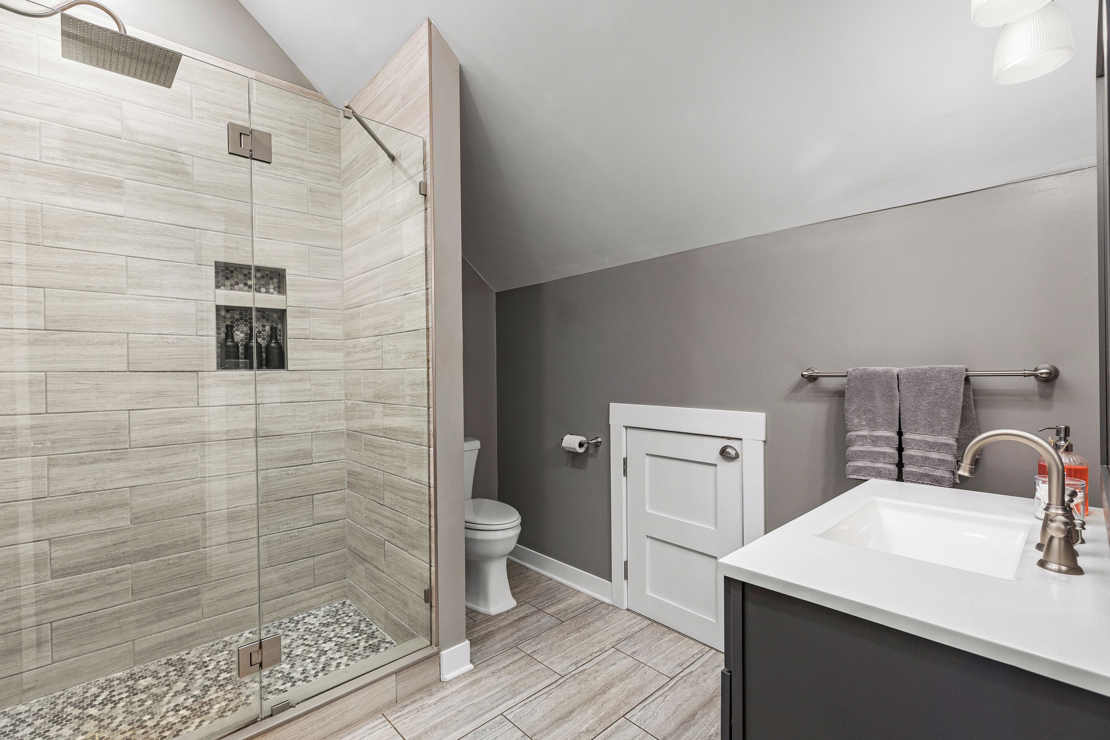 A modern bathroom with a shower, toilet, and sink.