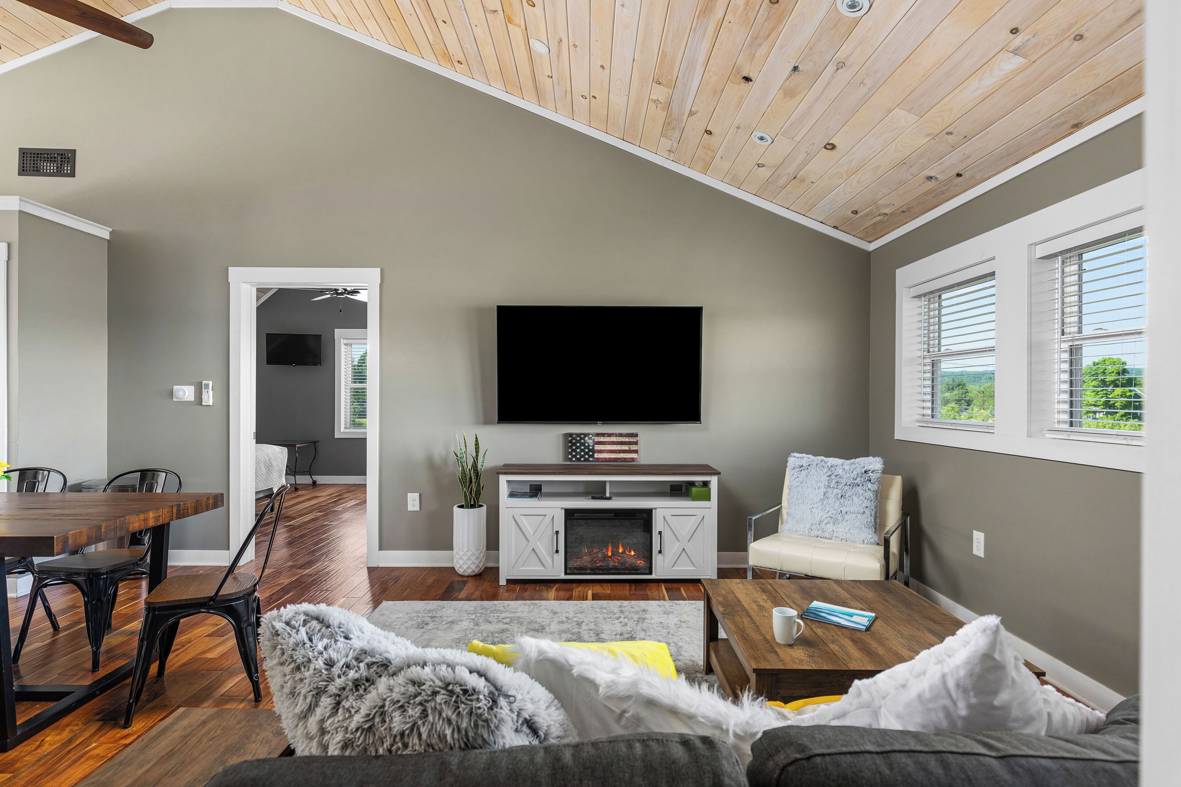 A modern living room with a fireplace, a dining area, and a TV mounted on the wall.
