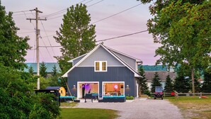 A two-story building with a garage, a covered outdoor seating area, and a gravel driveway. - Pleasant Valley Resort (Arcadia)