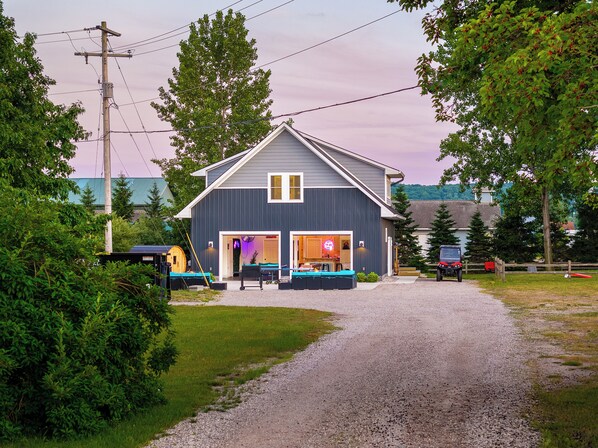 A two-story building with a garage, a covered outdoor seating area, and a gravel driveway. - Pleasant Valley Resort (Arcadia)