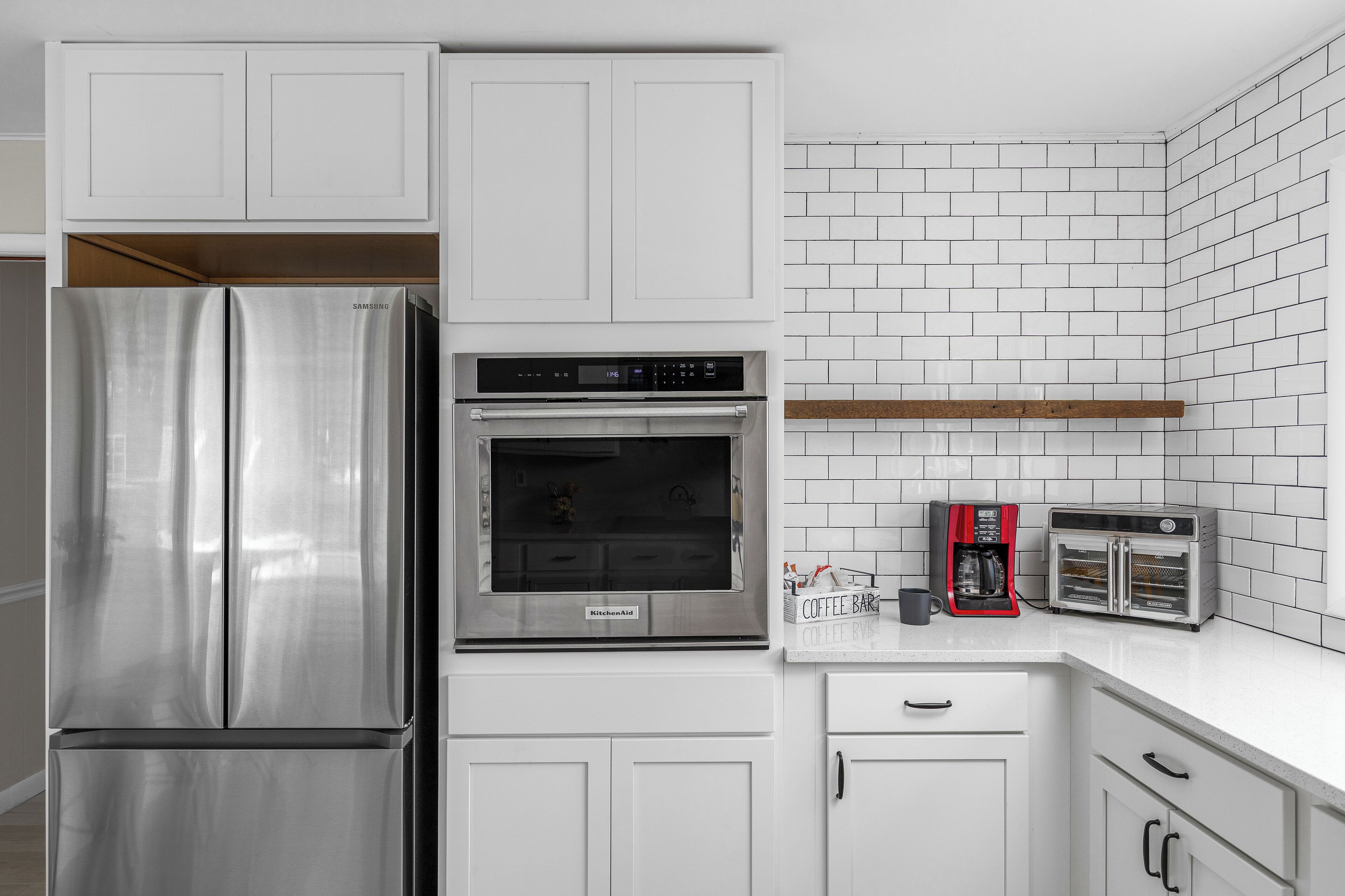 Eine moderne Küche mit Edelstahlkühlschrank, Einbauofen, Kaffeemaschine und Toaster.