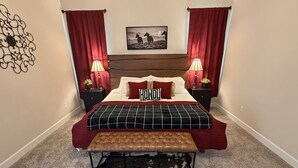 A bedroom with a bed, two bedside lamps, a headboard, a cowhide rug, and a wall decoration.