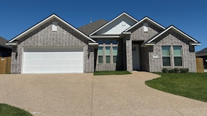 A two-story house with a garage, a covered porch, and a well-maintained lawn.