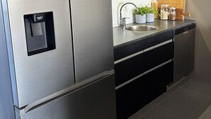 Una cocina moderna con electrodomésticos de acero inoxidable, un lavamanos integrado y cestas de almacenamiento en la encimera.