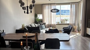Una sala de estar moderna con comedor, que incluye un sofá, una mesa de centro con velas y una botella de champán.