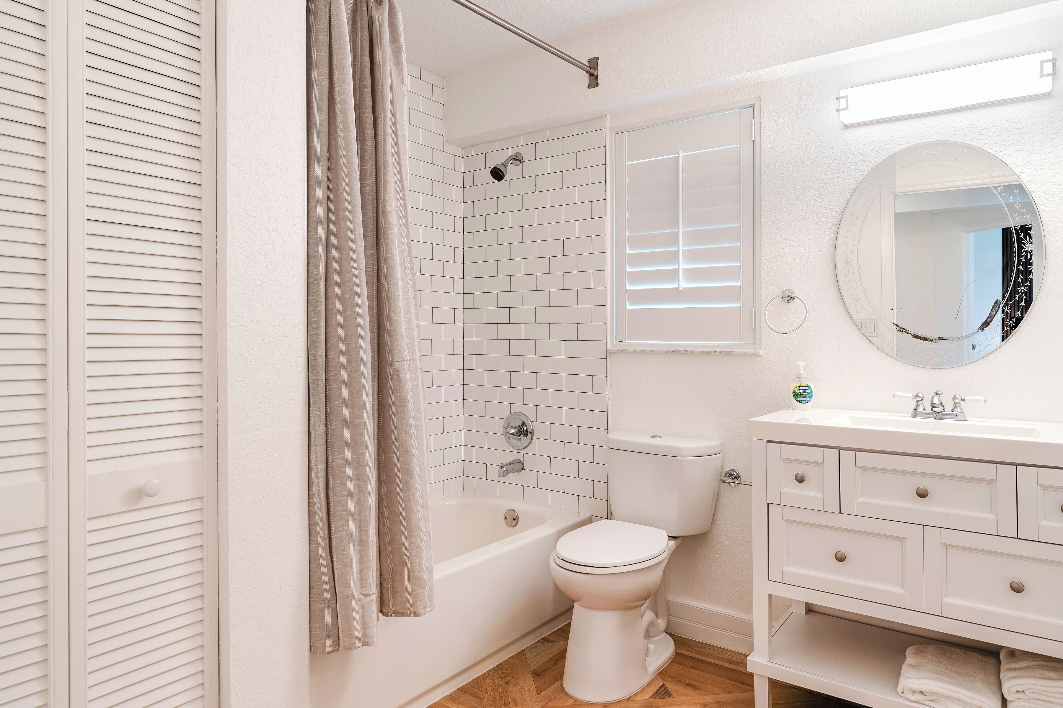 A bathroom with a white bathtub, toilet, and vanity with drawers.