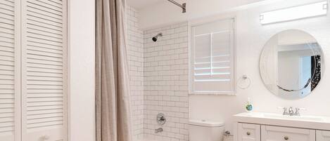 A bathroom with a white bathtub, toilet, and vanity with drawers.