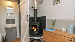 Ein gemütliches Zimmer mit Kaminofen, einem Holztisch, einem Spiegel und einem kleinen Waschbecken.