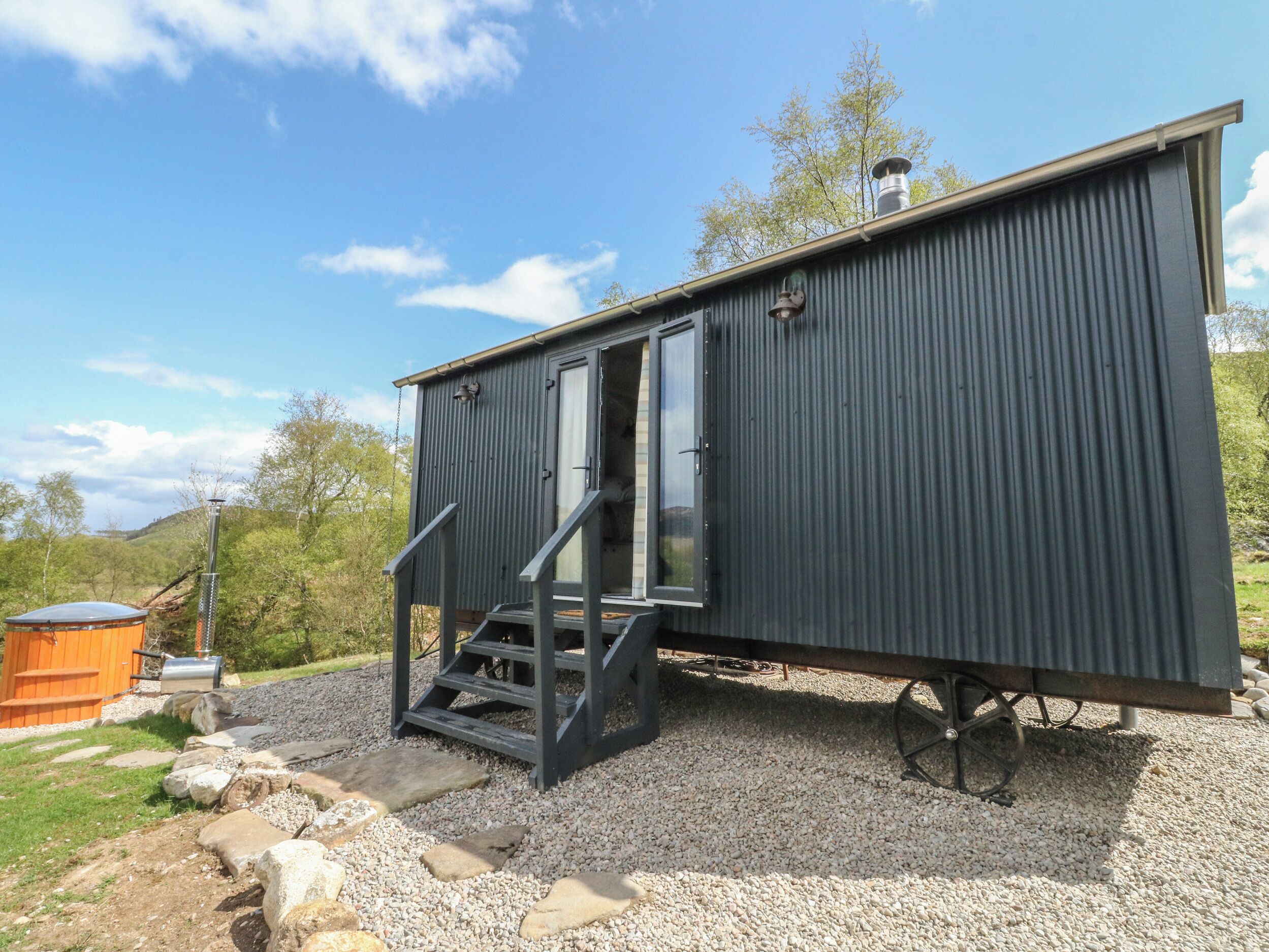 A compact, dark-colored cabin with a sliding door and a small set of stairs leading to a deck.
