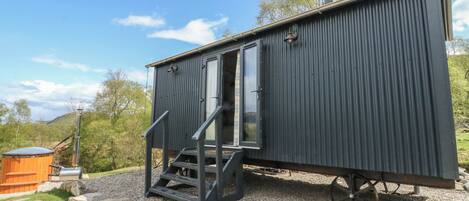 A compact, dark-colored cabin with a sliding door and a small set of stairs leading to a deck.