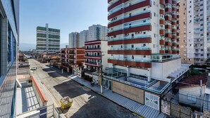 Un edificio residencial de varios pisos con balcones, un acceso con portón y una vista despejada de la calle.