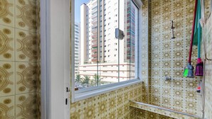 Un baño con baldosas estampadas, una ventana y vistas de edificios altos al exterior.