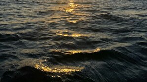 A sunset over a body of water with a clear horizon.
