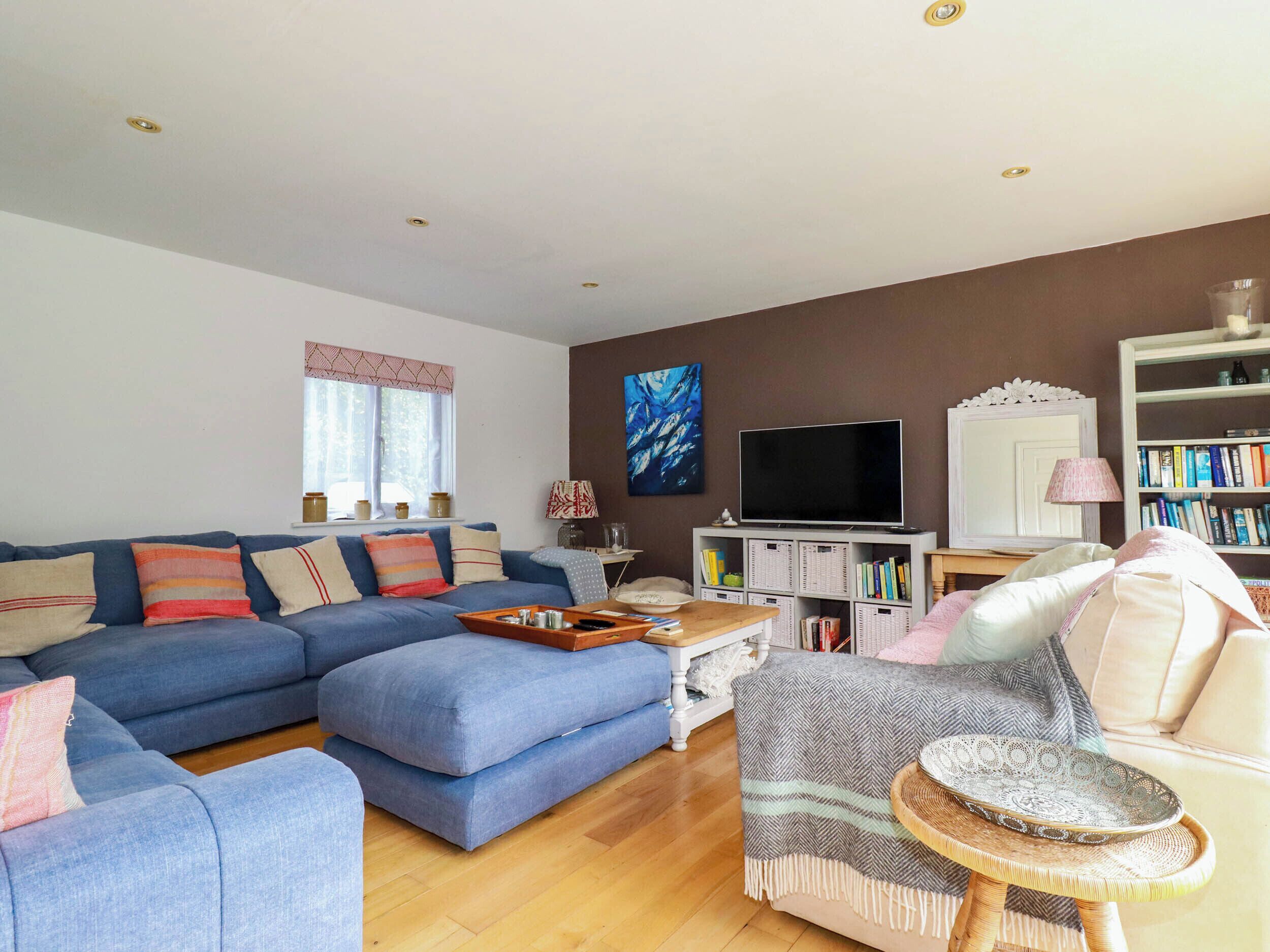 A living room with a blue sofa, a television, a bookshelf, and a lamp.
