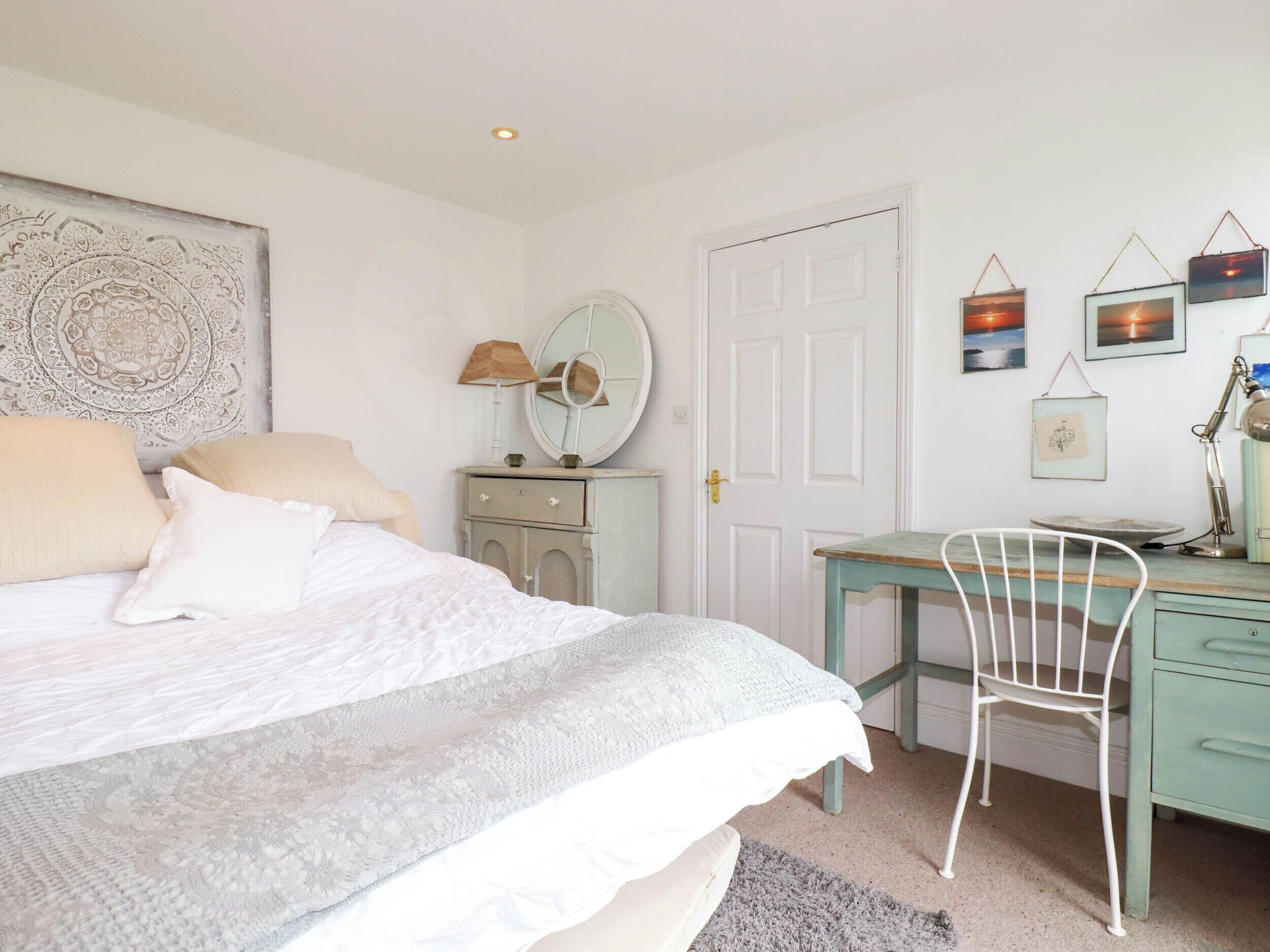 Een slaapkamer met een bed, een bureau, een stoel, een kast en een deur.