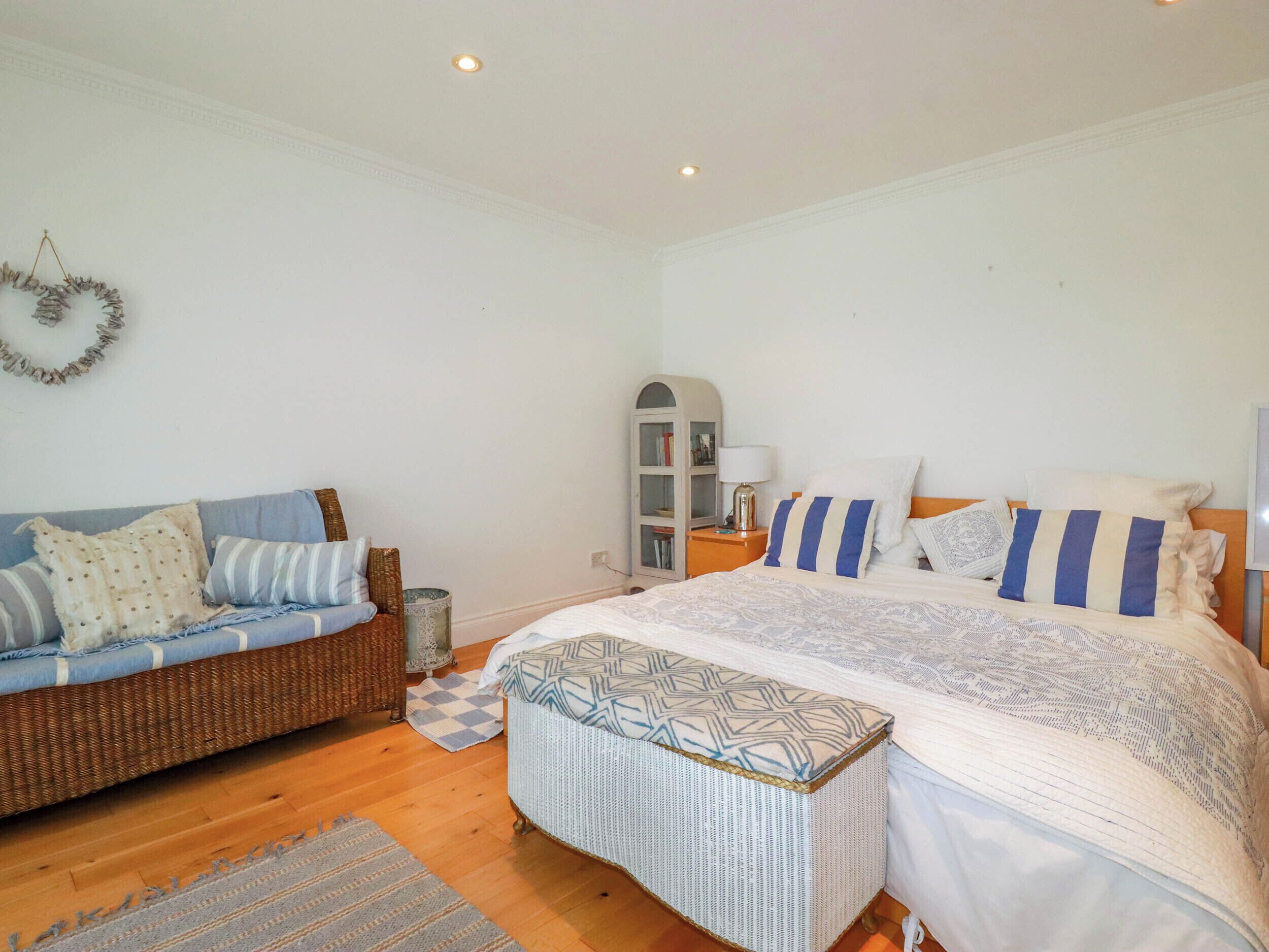 A bedroom with a bed, a sofa, a small cabinet, and a decorative wreath on the wall.