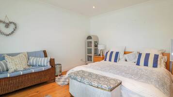 A bedroom with a bed, a sofa, a small cabinet, and a decorative wreath on the wall.