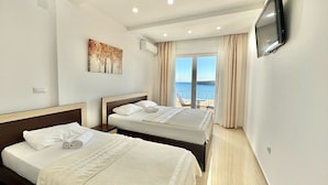 Une chambre d ’hôtel avec deux lits, une télévision et vue sur la mer.