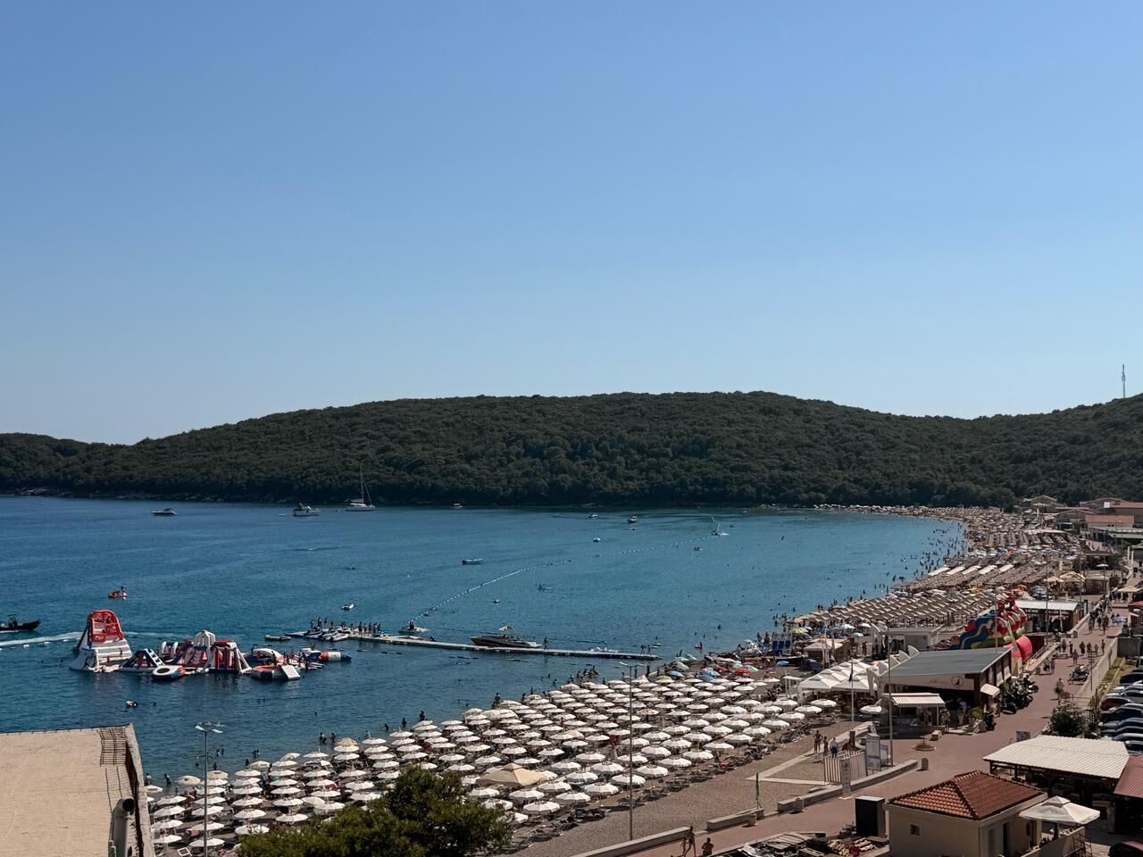 Eine Küstenlandschaft mit Strand, Booten und Sonnenschirmen.