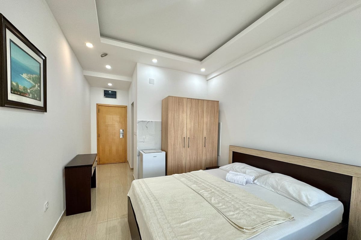 A hotel room with a bed, a wardrobe, a small desk, and a bathroom.