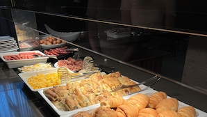 Un buffet proposant une variété de plats, notamment des viandes, des fromages et des pâtisseries.