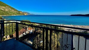 Un balcon offrant une vue sur un paysage côtier, comprenant une plage et une montagne.