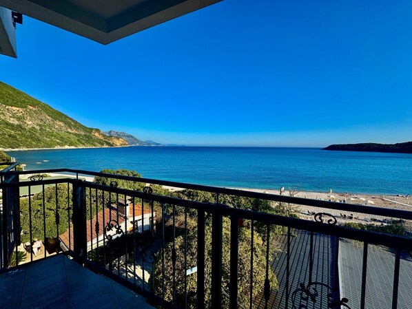 Un balcón con vista a un paisaje costero, que incluye una playa y una montaña.