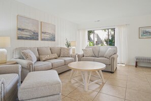 A modern living room with a beige sofa set, a round coffee table, and a bench.