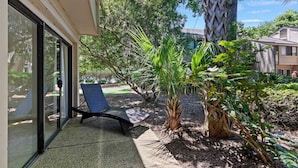 A patio area with a chair, a palm tree, and a small garden.