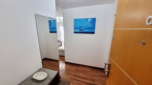 A hallway with wooden flooring, a small table with a basket, and two framed pictures on the walls. - Centrico y muy Completo Departamento (La Plata)