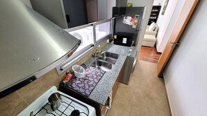 A compact kitchen with a gas stove, stainless steel sink, and a refrigerator. - Centrico y muy Completo Departamento (La Plata)