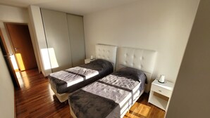 A bedroom with two beds, a nightstand, a bedside table, and a wardrobe. - Centrico y muy Completo Departamento (La Plata)
