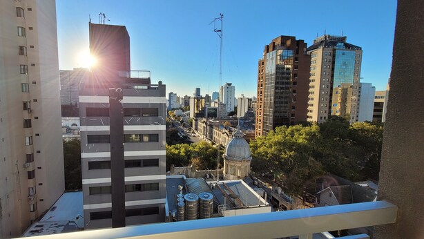 A cityscape with modern buildings, a clear sky, and the sun shining. - Centrico y muy Completo Departamento (La Plata)