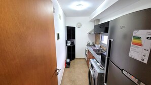 A compact kitchen with a refrigerator, stove, and microwave. - Centrico y muy Completo Departamento (La Plata)
